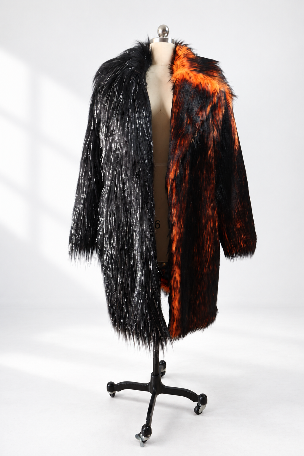 Black and fiery orange oversized faux fur coat displayed on a mannequin, showing its long shaggy texture, contrasting colors, and open-front design.